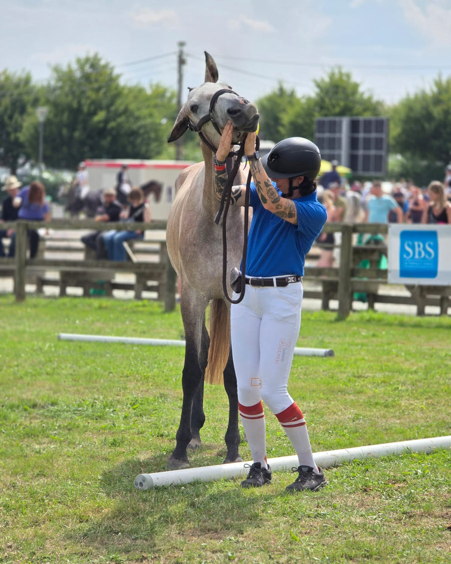 Laura de la Sellerie Eldorado, sellerie à Liège, avec son jeune cheval gris en concours
